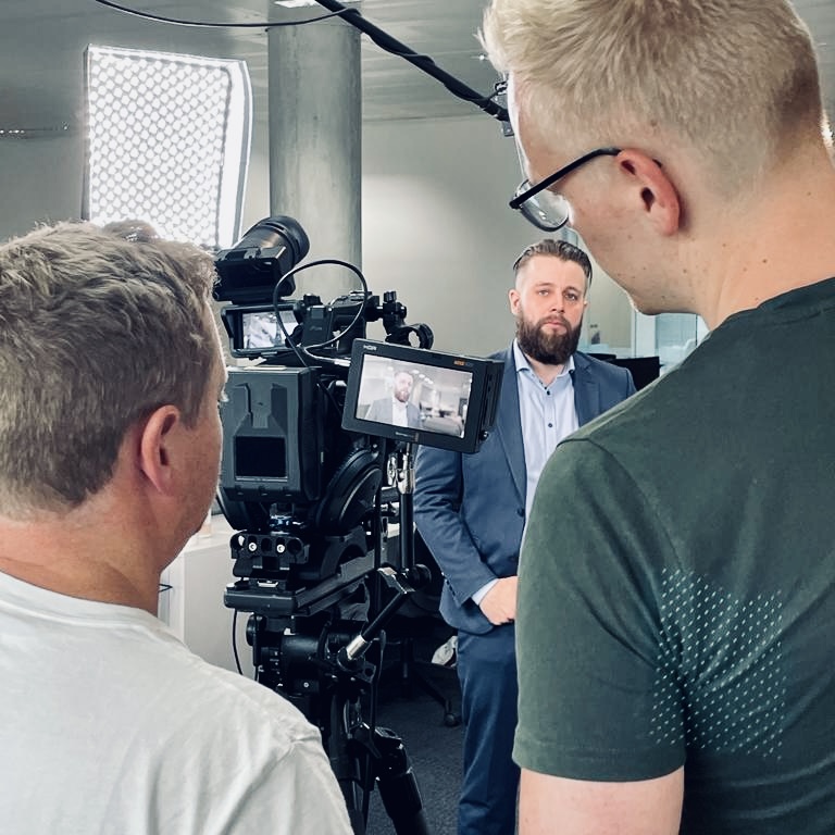 Film crew filming corporate video presenter in professional studio - Zealous Media