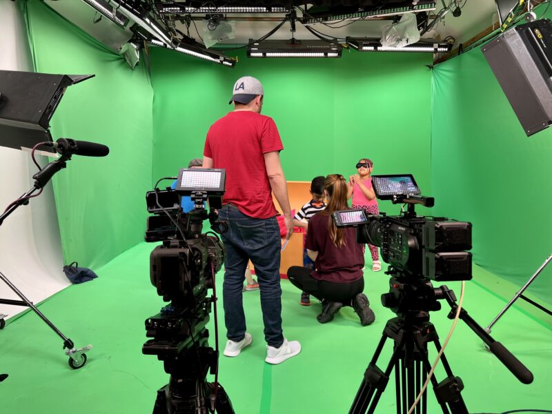 Video production crew directing children on green screen studio shoot - Zealous Media