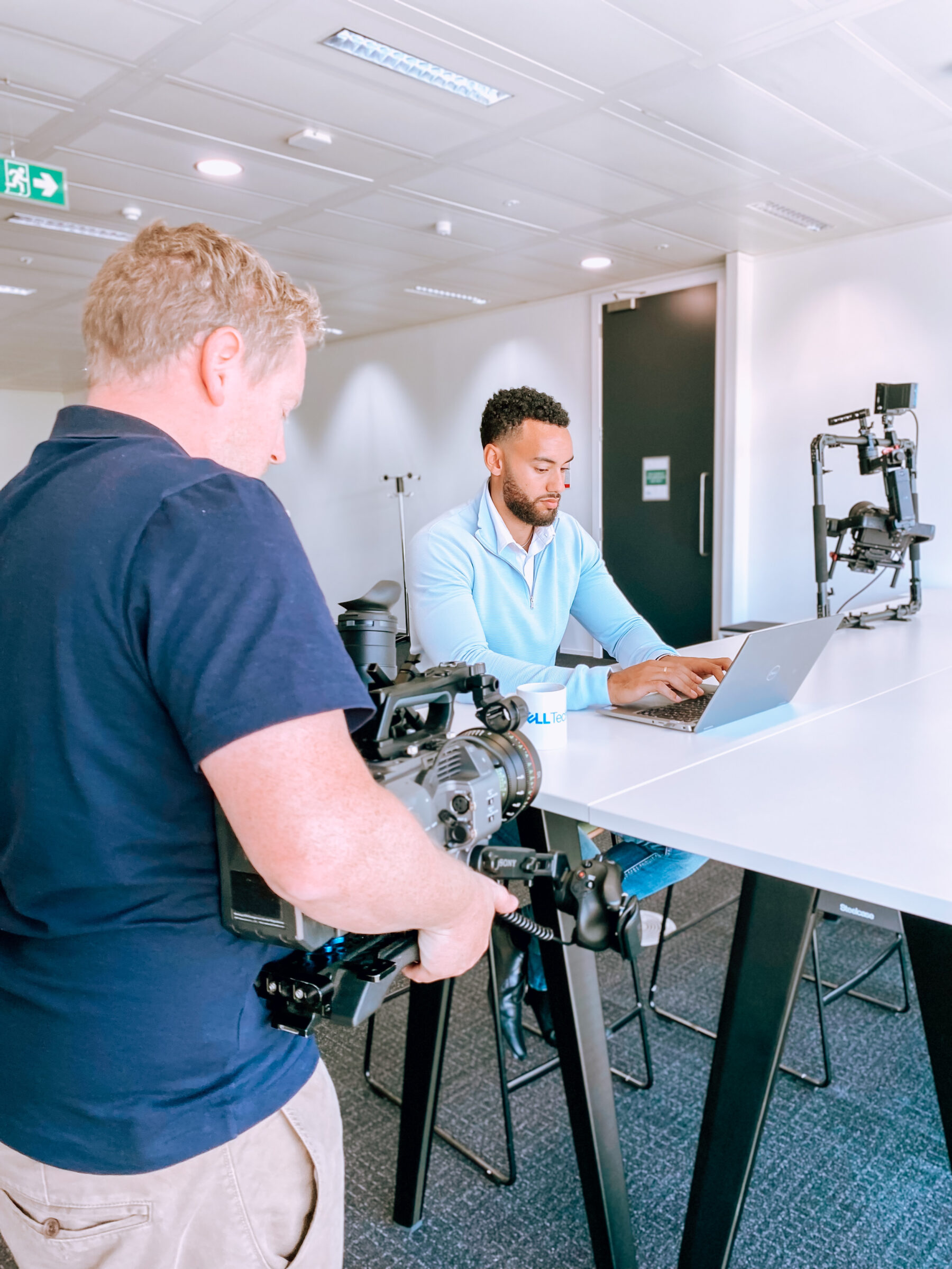 Cameraman filming presenter laptop modern office