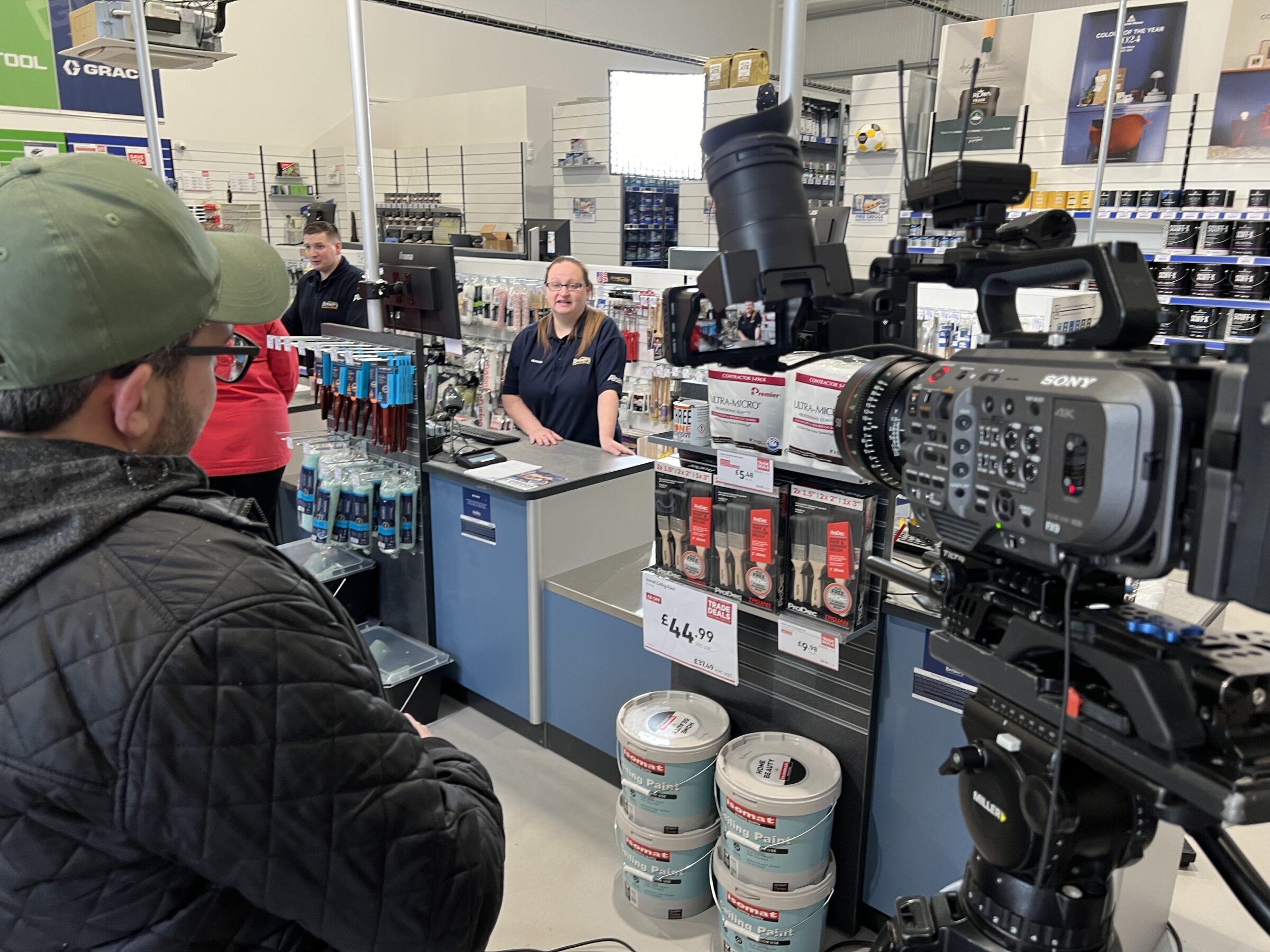 Director watching monitor filming trade store staff